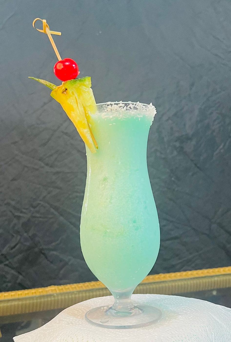 Coctel tropical azul con piña y cereza